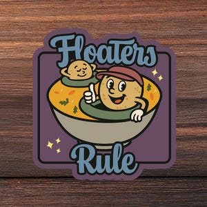 Puede incluir: Una taza de cerámica blanca con asa negra y el texto "But First, Coffee" en negrita negra. La taza se encuentra sobre un fondo borroso, sugiriendo un ambiente acogedor.