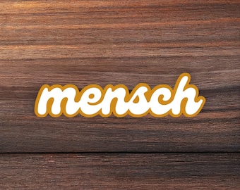 Könnte beinhalten: Ein Aufkleber mit dem Wort mensch in einer weißen, abgerundeten Schreibschrift mit einer dicken, senfgelben Umrandung. Die Buchstaben sind in einer einzigen Zeile angeordnet und in einem fließenden, handschriftlichen Stil verbunden.