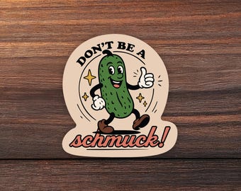Könnte beinhalten: Ein gestanzter Aufkleber mit einer grünen Comic-Gewürzgurke mit Armen und Beinen, die den Daumen hochhält. Die Gurke ist von vierzackigen Sternen umgeben, mit dem Text "DON'T BE A" darüber und "schmuck!" in roter Schreibschrift unter der Figur.