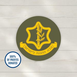May include: A circular olive green sticker featuring the yellow emblem of the Israel Defense Forces, which includes a Star of David, a sword, and an olive branch. Below the emblem is a yellow banner with Hebrew text. A small blue circle reads 100% OF PROFITS DONATED.