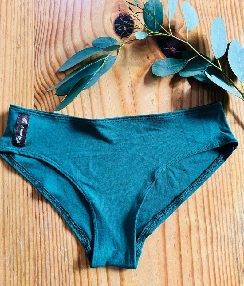 May include: Teal green underwear with a small black label that says "wild design" on the front.