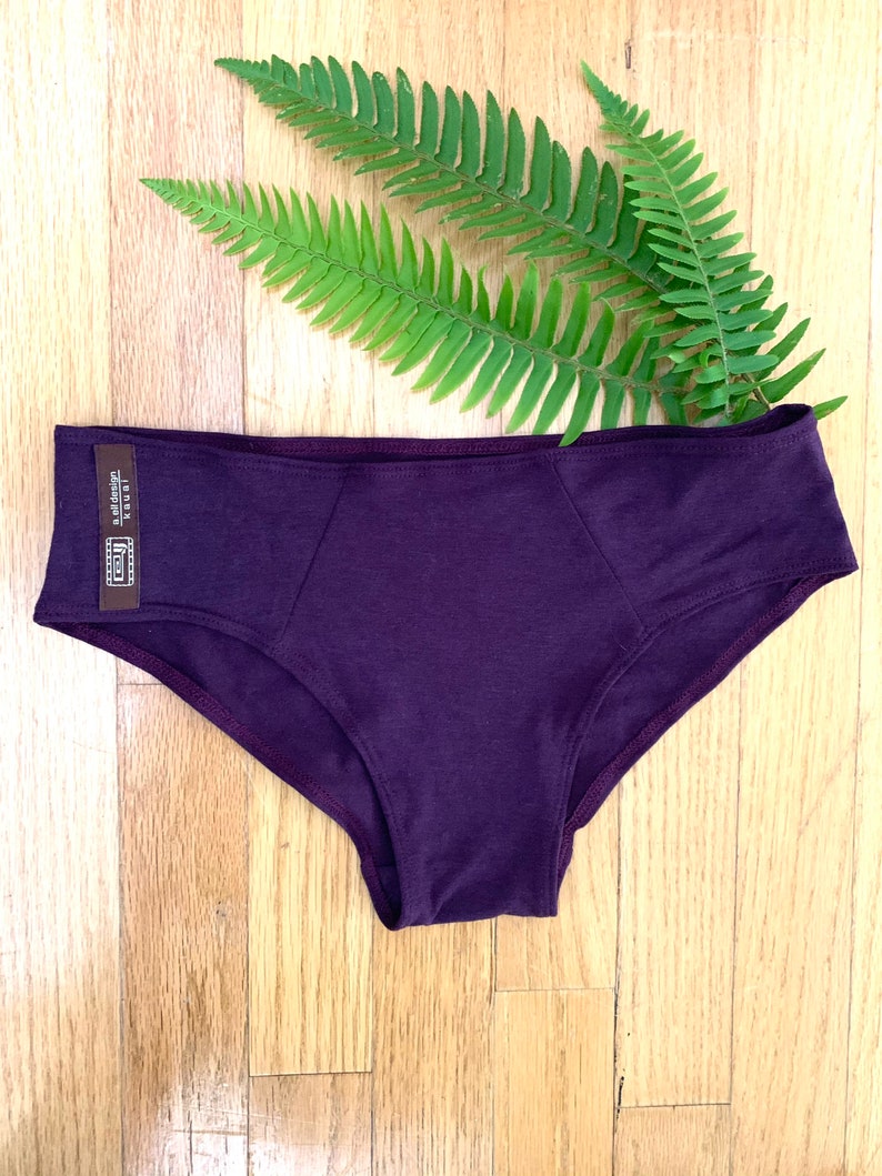 May include: Purple underwear with a brown tag that says "Made in USA" and "soft design".