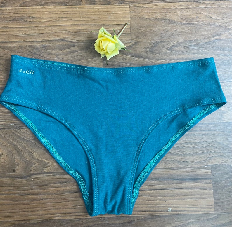 May include: Teal blue underwear with a green trim and the text "a.e.u" on the front.