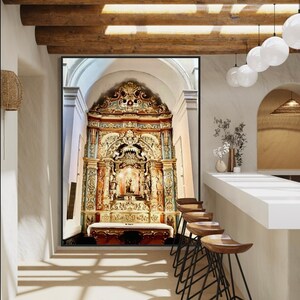 May include: An ornate gold-coloured altar with a statue of a person in the centre. The altar is in a room with a wooden ceiling and white walls. There are wooden chairs in the foreground.