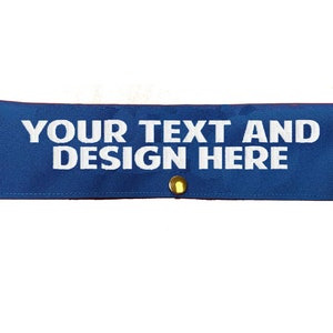 May include: Blue fabric patch with white text that reads "YOUR TEXT AND DESIGN HERE". The patch has four gold metal grommets.