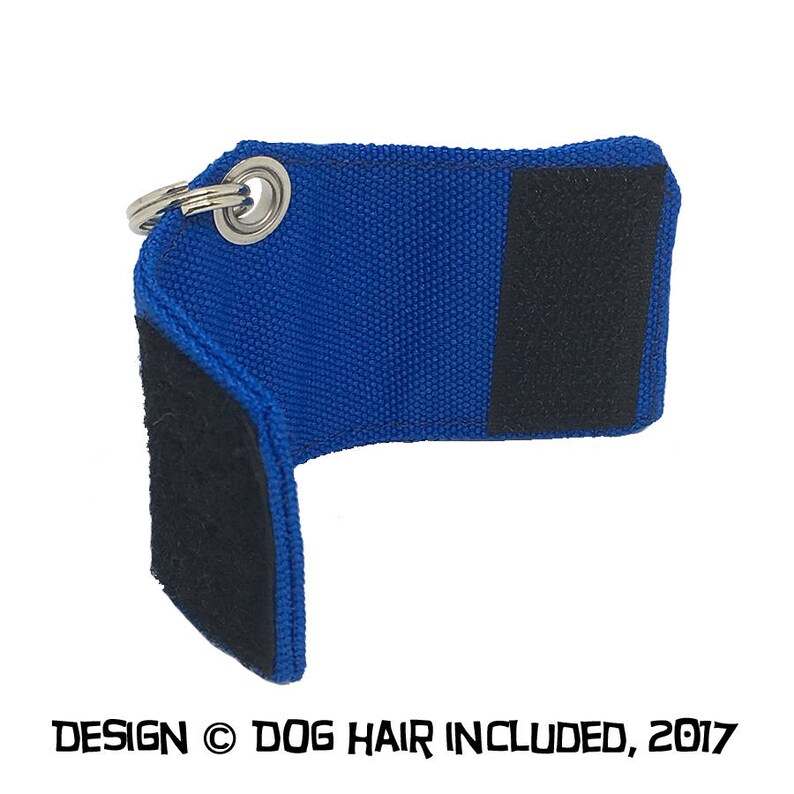 May include: Blue fabric key chain with a black velcro patch and a silver metal ring.  The text "DESIGN &copy; DOG HAIR INCLUDED, 2017" is printed on the bottom of the image.