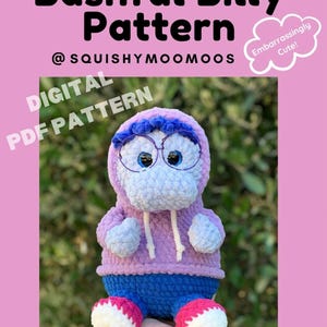May include: A crochet pattern for a purple and blue plush toy with glasses, a hoodie, and pants. The pattern is called "Bashful Billy" and is available as a digital PDF download from @squishymoomoos. The text "Embarrassingly Cute!" is written in a cloud shape.