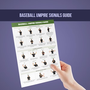 May include: A baseball umpire signals guide with diagrams and text, held by a hand. The guide displays various signals for plays, including pitch, infield fly, and safe/out calls. The title "Baseball Umpire Signals Guide" is at the top.