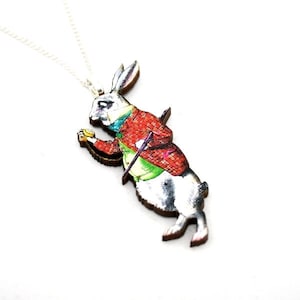 May include: A white rabbit wearing a waistcoat and holding a pocket watch, depicted in a vintage illustration style, is the centerpiece of this wooden pendant necklace. The rabbit is in a running pose, with its ears perked up and its tail held high. The pendant is attached to a silver chain.