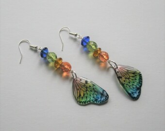 May include: A pair of dangle earrings featuring a rainbow butterfly wing charm and colorful glass beads. The beads are blue, green, orange, and yellow.