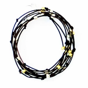 May include: A brown leather wrap bracelet with silver and gold beads.