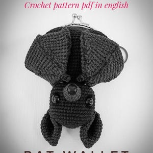 May include: A black crochet bat wallet with a silver clasp, hanging upside down. The bat has large, textured wings and small, round eyes. The text "Crochet pattern pdf in english" and "BAT WALLET" are visible.