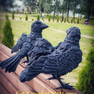 May include: Two dark blue crochet raven sculptures are perched on a wooden bench. The birds have detailed feather patterns and are set against a blurred park background. Text on the bench reads "Set Crochet Patterns PDF IN ENGLISH."