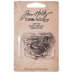 May include: A package of Idea-ology loop pins. The package has a clear plastic window showing the silver-colored pins. The card backing is tan with black text that reads "Tim Holtz idea-ology LOOP PINS". The package contains 24 pins.