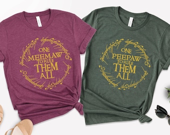 May include: Two t-shirts, one burgundy and one green, with the text "ONE MEEMAW TO RULE THEM ALL" and "ONE PEEPAW TO RULE THEM ALL" in a gold ring design. The shirts are made of a soft material and have a crew neck.