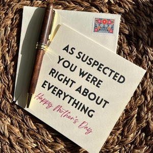 May include: A greeting card with the text "AS SUSPECTED YOU WERE RIGHT ABOUT EVERYTHING Happy Mother's Day" is displayed with a pen, envelope, and a floral stamp. The pen is brown with gold accents.