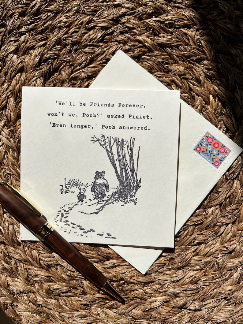 May include: A greeting card with a Winnie the Pooh illustration and the quote "We'll be Friends Forever, won't we, Pooh?" A wooden pen and an envelope with a floral stamp are also visible.