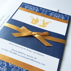 Op de afbeelding: Een blauwe en witte uitnodiging met een gouden lint en een gouden kroonontwerp. De tekst op de uitnodiging luidt "Given with love by: Family and Friends. Please RSVP by August 24 to 516.770.2482 or eriroberts@hotmail.com"