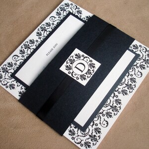 May include: Black and white wedding invitation with a black envelope and a decorative border. The invitation says "Please Join".