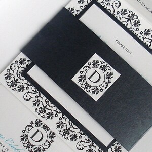 May include: A black and white wedding invitation with a decorative floral pattern. The invitation has a black envelope with a white monogram of the letter "D" in the center. The text on the invitation reads "Please Join" and "Celebrate with us".