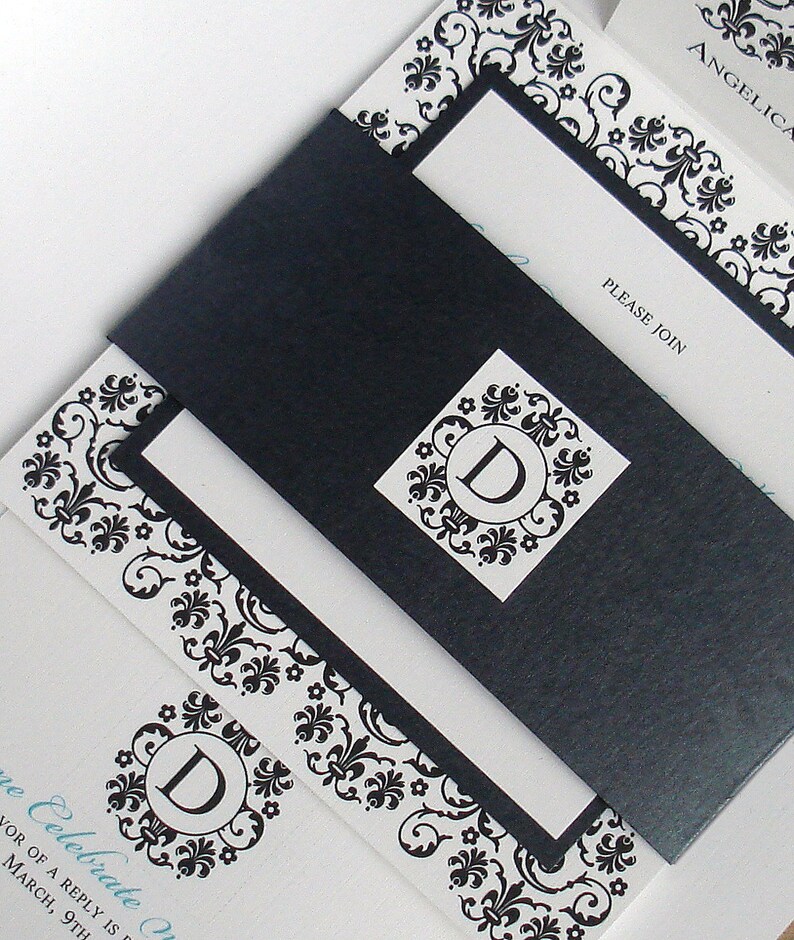 May include: A black and white wedding invitation with a decorative floral pattern. The invitation has a black envelope with a white monogram of the letter "D" in the center. The text on the invitation reads "Please Join" and "Celebrate with us".