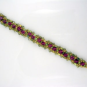 May include: A gold beaded bracelet with pink and green square beads. The bracelet has a toggle clasp.