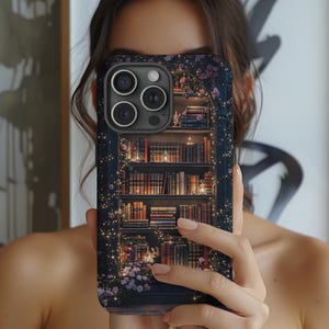May include: A phone case with a detailed illustration of a bookshelf filled with books. The design includes fairy lights, flowers, and a dark blue background. The case has a glossy finish and a camera cutout.