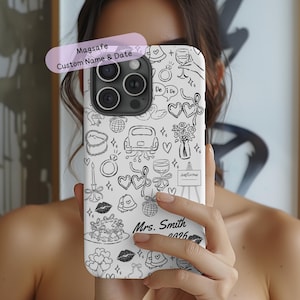 May include: White phone case with a black doodle design featuring wedding-themed illustrations. The case includes the text "Magsafe Custom Name & Date" and "Mrs. Smith 2026".