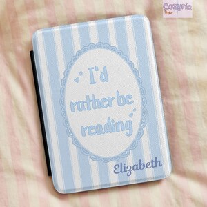 Op de afbeelding: Een rechthoekige e-reader hoes met een verticaal gestreept patroon in lichtblauw en wit. Het midden toont een wit ovaal met een geschulpte rand met de tekst I'd rather be reading en de naam Elizabeth in een blauw lettertype.
