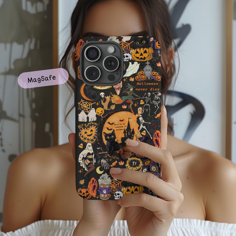 May include: A black smartphone case featuring a vibrant Halloween-themed pattern with orange pumpkins, black cats, ghosts, skeletons, spider webs, and a haunted house. The text "Halloween never dies" and "This is my haunted hotspot" are printed on the case.
