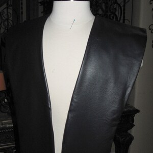 May include: Black faux leather fabric for crafting projects. The fabric is shown draped over a dress form.