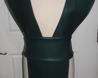 May include: A dark green faux leather vest with a deep V-neckline and a wide belt. The vest has a long, flowing skirt.