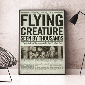 May include: A framed vintage newspaper print with the headline "FLYING CREATURE SEEN BY THOUSANDS." The black and white image features a group of people looking up in shock. The date is Tuesday, Jan. 19, 1909.