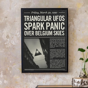 May include: A framed black and white print with the headline "TRIANGULAR UFOS SPARK PANIC OVER BELGIUM SKIES." The image depicts a triangular object in the sky above buildings. The date "Friday, March 30, 1990" is at the top of the print.