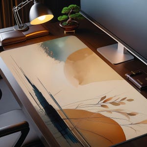 Op de afbeelding: Een rechthoekige bureaumat met een abstract aquarelontwerp in beige, blauwe en bruine tinten. Het kunstwerk toont een grote, lichtgekleurde cirkel en lineaire elementen. De mat ligt op een donkerhouten bureau, met een lamp en monitor.