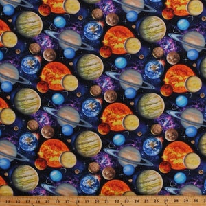 May include: A colorful fabric with a repeating pattern of planets and stars on a dark blue background. The planets are in various shades of orange, yellow, brown, and blue. The stars are white and scattered throughout the fabric.
