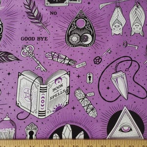 May include: A purple fabric with a repeating pattern of occult symbols. The design includes a Ouija board, bats, keys, a book of spells, bundles of sage and lavender, and an all-seeing eye. The words "GOOD BYE" and "NO" are also visible.