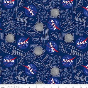 May include: A navy blue fabric with a repeating pattern of NASA logos, moon illustrations, and text blocks. The NASA logo features a red swoosh. The text includes phrases like "Exploring" and "Innovating".