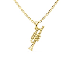 Puede incluir: Un collar dorado con un colgante de trompeta. El colgante es una réplica en miniatura detallada de una trompeta, con válvulas y campana visibles. La cadena es de estilo eslabón delicado, también en oro. El collar se muestra sobre un fondo blanco.