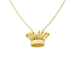 May include: A gold-colored necklace featuring a pendant shaped like a chef's hat. The pendant has a detailed, textured design and hangs from a delicate chain. The necklace is a culinary-themed accessory.