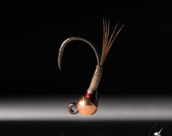 May include: A small, copper-colored fly fishing hook with a red and brown thread wrap and a few feathers extending from the top.