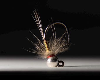 May include: A small, silver and red fly fishing lure with a brown and green body and a white feather tail.