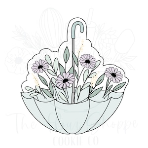 Puede incluir: Un cortador de galletas con forma de paraguas con flores en su interior. El paraguas es de color azul claro y las flores son de color morado y amarillo.