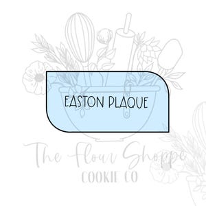 May include: A light blue plaque with rounded corners, featuring the text "EASTON PLAQUE" in black. The plaque is set against a backdrop of baking tools and floral illustrations, with the words "The Flour Shoppe Cookie Co" below.
