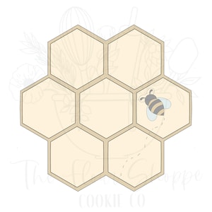 May include: A beige honeycomb cookie cutter with a bee flying out of one of the cells. The bee is gray and black with white wings.