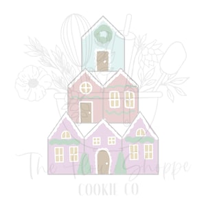 May include: A stacked cookie cutter design featuring pastel-colored gingerbread houses. The houses are in shades of pink, purple, and blue, with white trim and windows. The text "The Flour Shoppe Cookie Co" is at the bottom.