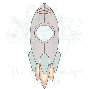 May include: A light gray rocket ship cookie cutter with a round window, light blue fins, and peach-colored flames. The rocket has a vintage, hand-drawn style. The text "The Shoppe Cookie Co" is at the bottom.