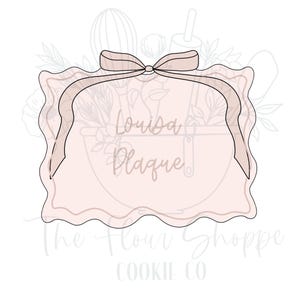 May include: A white cookie cutter with a scalloped edge and a pink bow on top. The cookie cutter is shaped like a rectangle with rounded corners. The text "Louisa Plaque" is visible inside the cookie cutter.