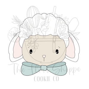 May include: A cookie cutter in the shape of a lamb's head with a light blue bow tie. The lamb has a fluffy white head and pink-lined ears. The text "The Flour Shoppe Cookie Co" is at the bottom.