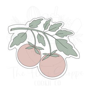 May include: A cookie cutter in the shape of two tomatoes on a vine with leaves. The tomatoes are a light pink color, and the leaves are a muted green. The text "The Flora Cookie Co" is at the bottom.